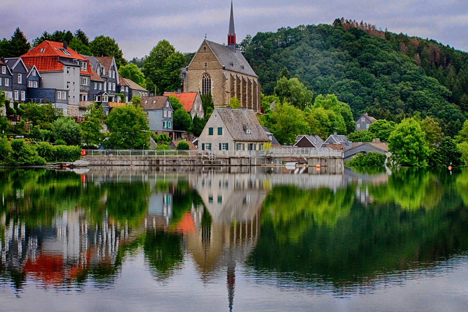 Beyenburger Stausee mit der Klosterkirche und Schieferhäusern, die sich im Wasser spiegeln
