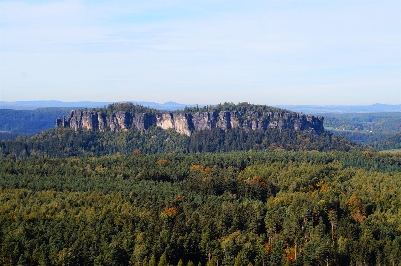 Der flache Tafelberg Pfaffenstein mit seinem Felskranz über weitem Wald in ersten Herbstfarben, am Horizont weitere Höhenzüge