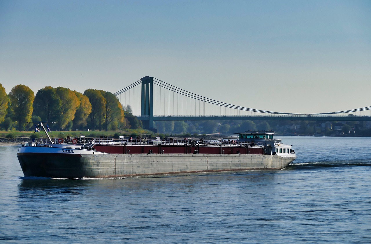 Frachtschiff auf dem Rhein vor der Rodenkirchener Brücke, am Ufer herbstliche Bäume