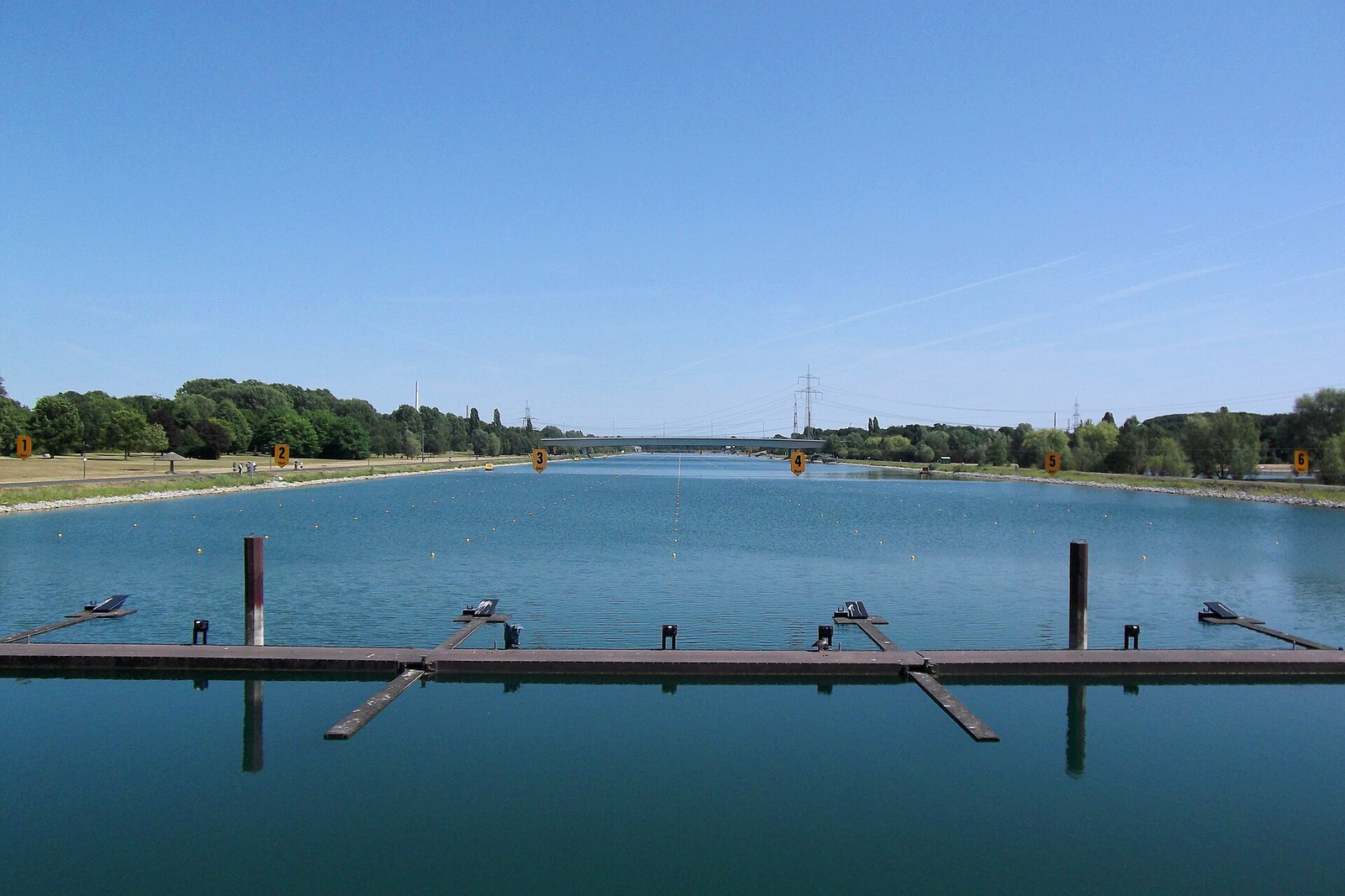Die Regattabahn am Fühlinger See mit Startanlage und Bahnnummern, an den Ufern Bäume