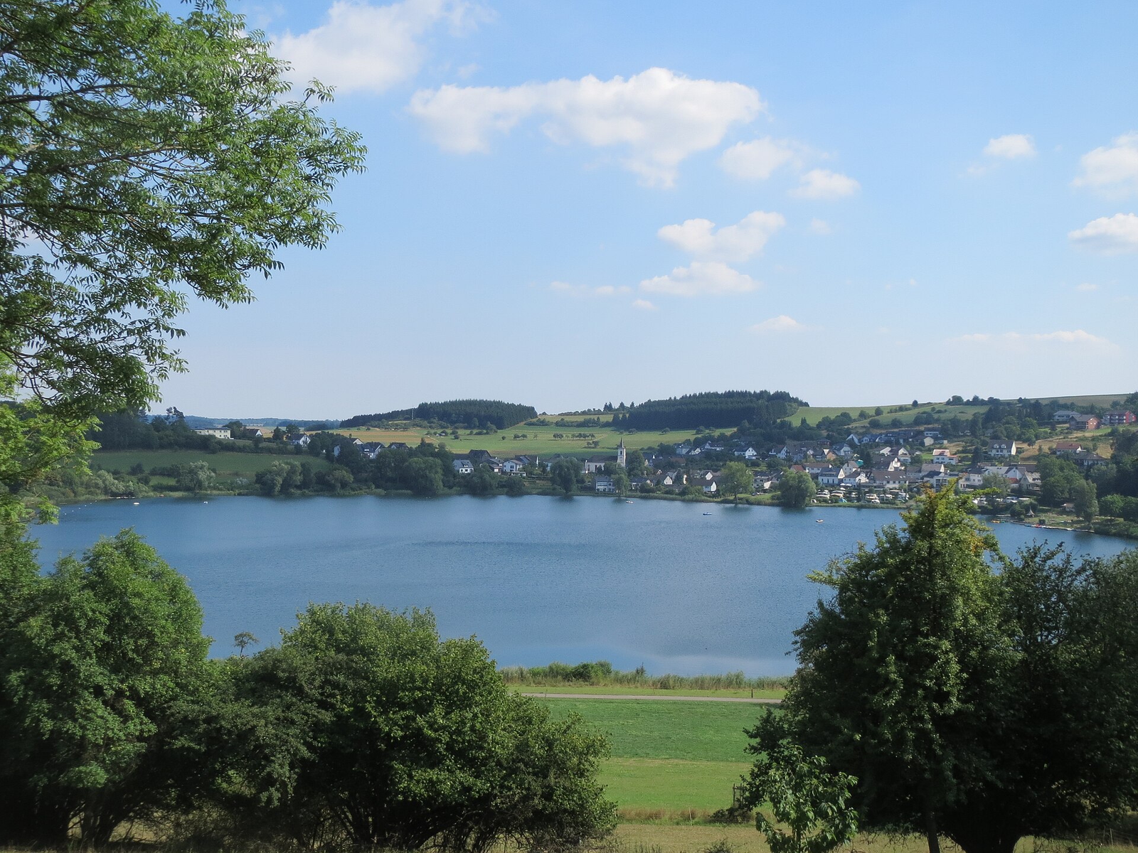 Das Schalkenmehrener Maar mit dem Dorf Schalkenmehren und seiner Kirche am gegenüberliegenden Ufer