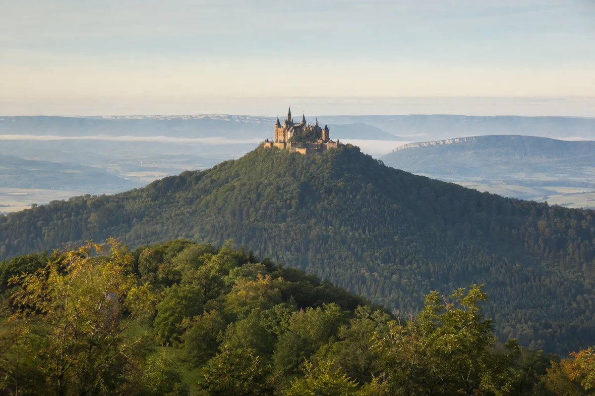 Burg Hohenzollern: Parkplatz Burg Hohenzollern: Burg Hohenzollern: vielgliedrige Gipfelburg auf isoliertem bewaldetem Kegel vor der Albkante