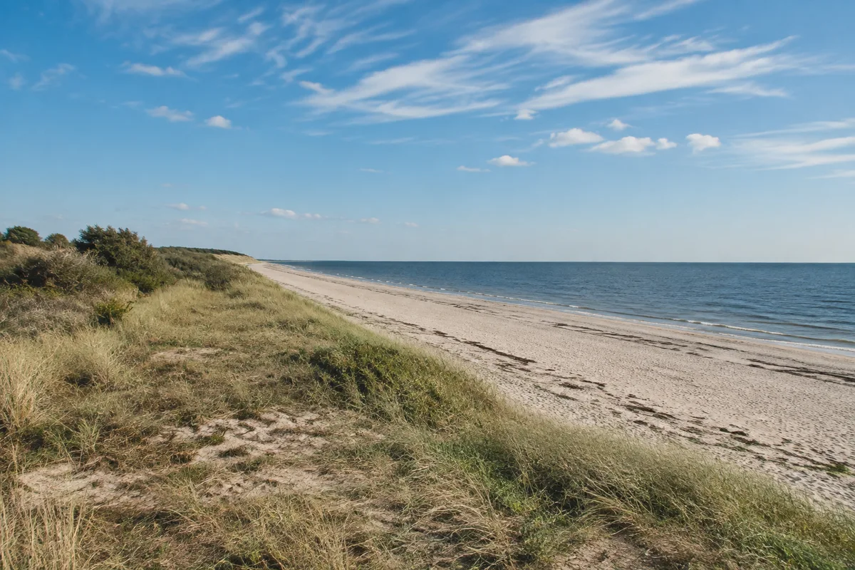 Utersumer Küste: Flacher schmaler Sandstrand mit niedriger grasiger Uferkante und weitem Nordseehimmel
