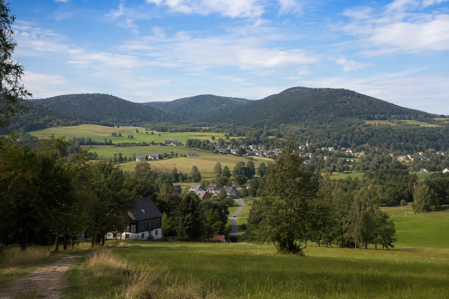 Großschönau: Großschönauer Landschaft: grüne Talwiesen mit einzelnen Umgebindehäusern vor bewaldeten rundlichen Vulkanbergen