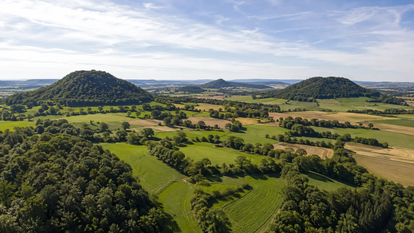 Hegau: Singen Friedingen Kirche: Hegauer Kegelbergland: Mehrere voneinander getrennte grüne Vulkankegel über weitem hügeligem Ackerland mit Feldhecken und Laubwald, keine erfundenen Burgen