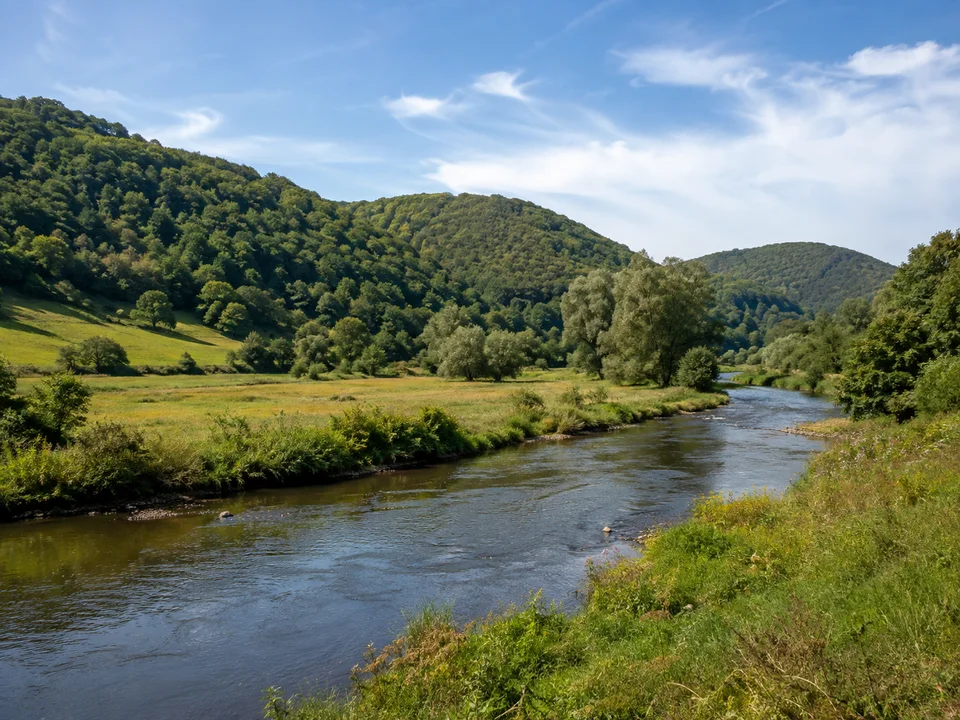 Lahnaue bei Biedenkopf: Mittelbreiter Fluss mit grünen Auenwiesen vor rundlichen bewaldeten Bergen