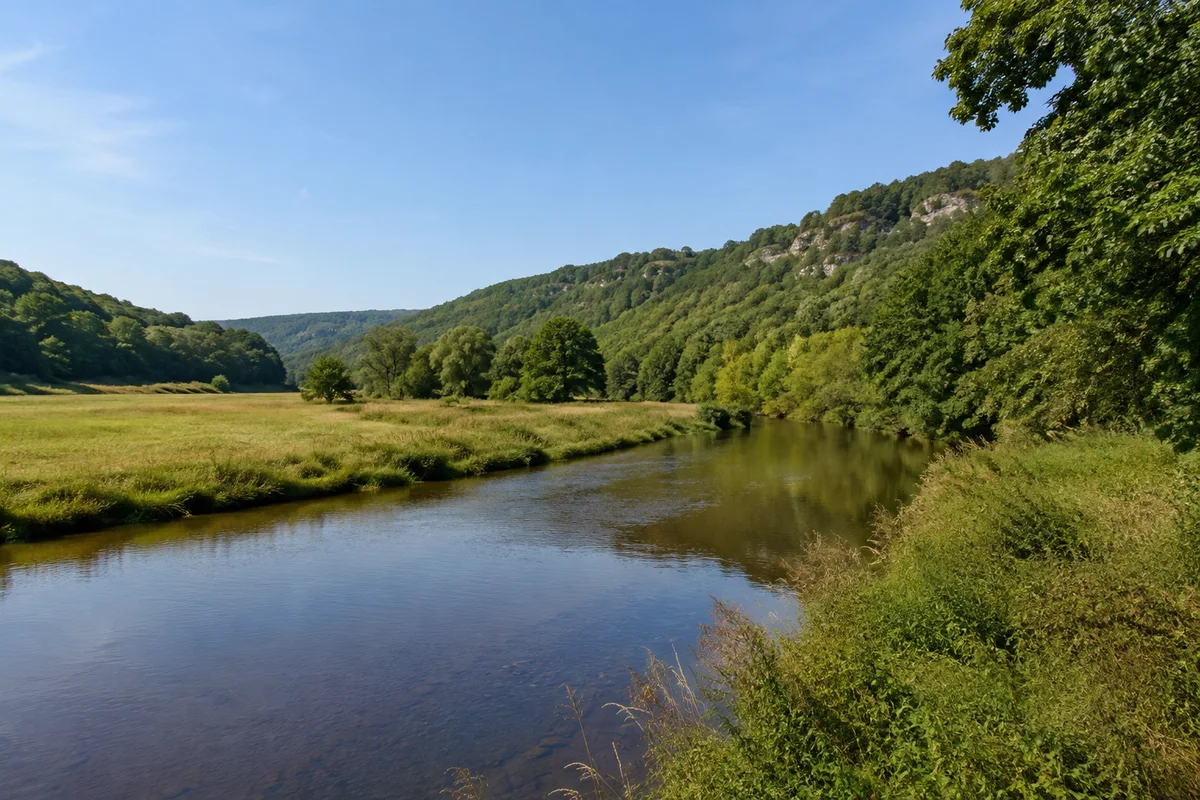 Mittelgroße ruhige Werra zwischen grünen Talwiesen und niedrigen bewaldeten Muschelkalkhöhen bei Mihla