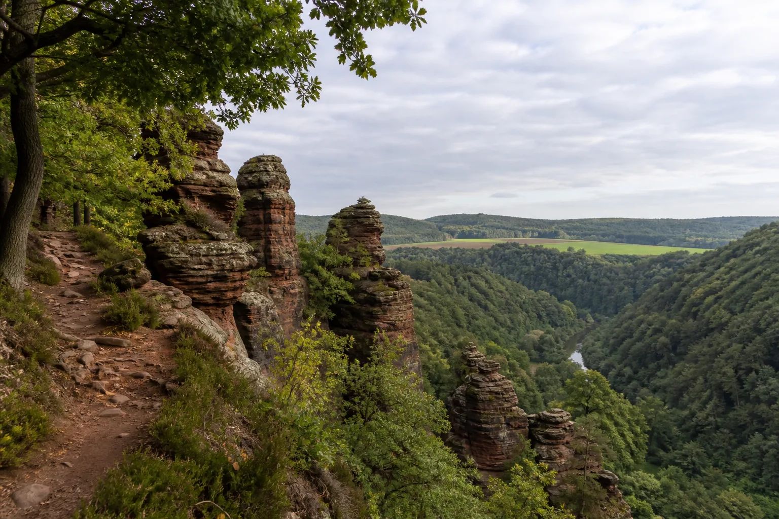 Waldpfad zwischen roten Buntsandsteinfelsen über dem Rurtal bei Nideggen
