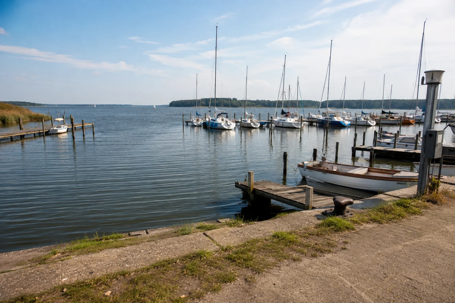 Mehrere Reihen von Segelbooten an Stegen im Lauterbacher Hafen mit Blick auf den Greifswalder Bodden