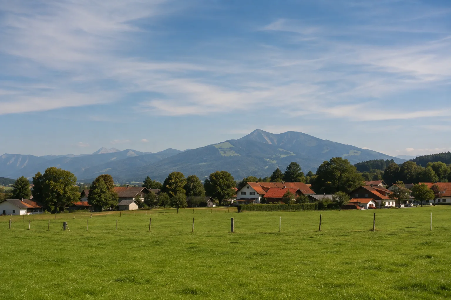 Pang bei Rosenheim: offene Wiesen, kleine Dorfhäuser und Gehölze vor fernen Bergen