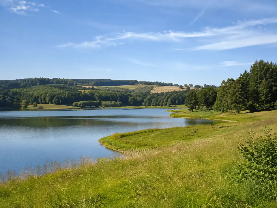 Aichstruter Seeumfeld: Kleine Stauseewasserfläche mit niedrigen grünen Ufern und Wald im sanften Keuperhügelland